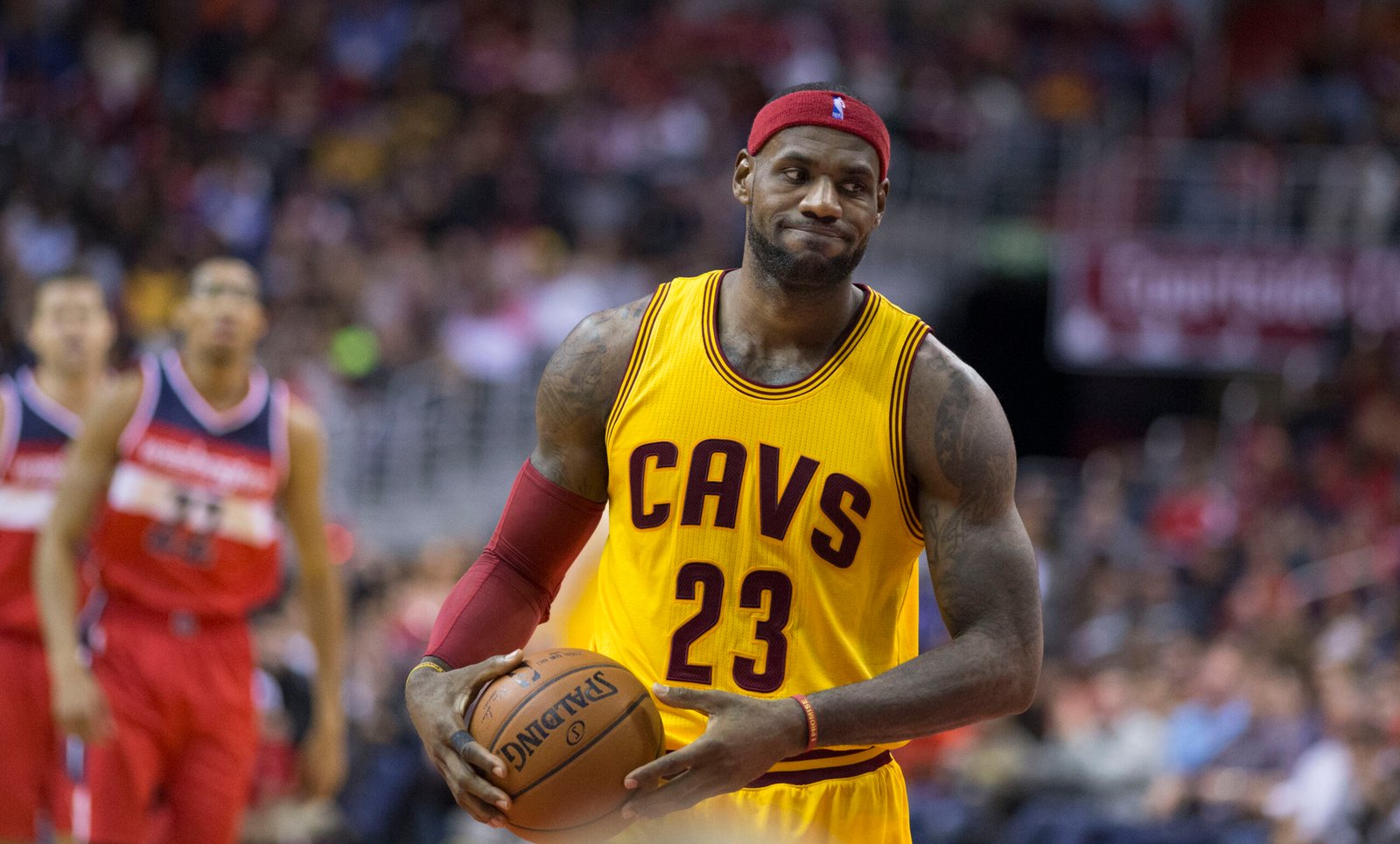 LeBron James in a yellow Cavaliers jersey holding the ball during a game, featured in an article about LeBron James net worth.