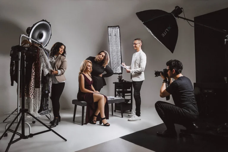 Photography team working in a studio as a photographer shoots a model while stylists and assistants prepare the scene.