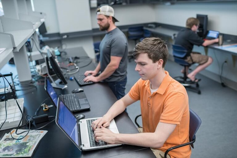 Students working on laptops and coding in a university computer lab.