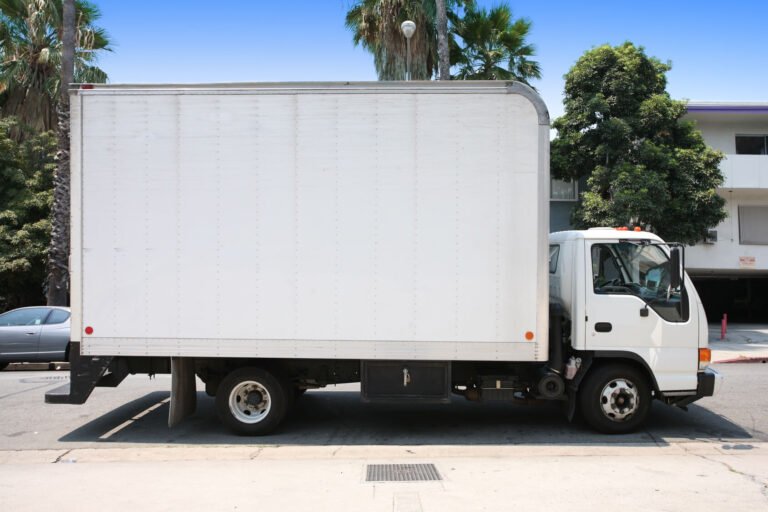White box truck parked on a city street, used for delivery and small freight services.